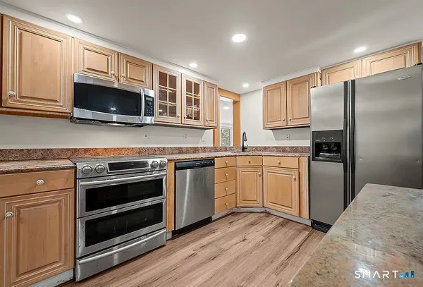 a kitchen with cabinets stainless steel appliances and wooden floor