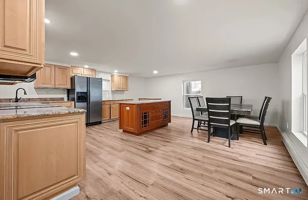 a kitchen with stainless steel appliances kitchen island granite countertop a table chairs sink and cabinets