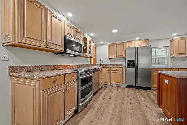 a kitchen with stainless steel appliances granite countertop a stove a sink and a refrigerator