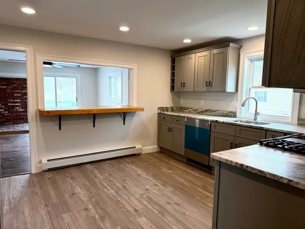 a kitchen with stainless steel appliances granite countertop a sink a stove top oven and wooden floors