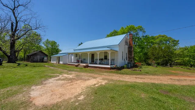 a view of a wooden house with a large yard and large trees