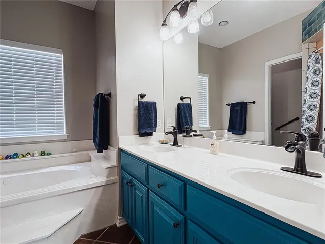 a bathroom with a double vanity sink a mirror and a bathtub