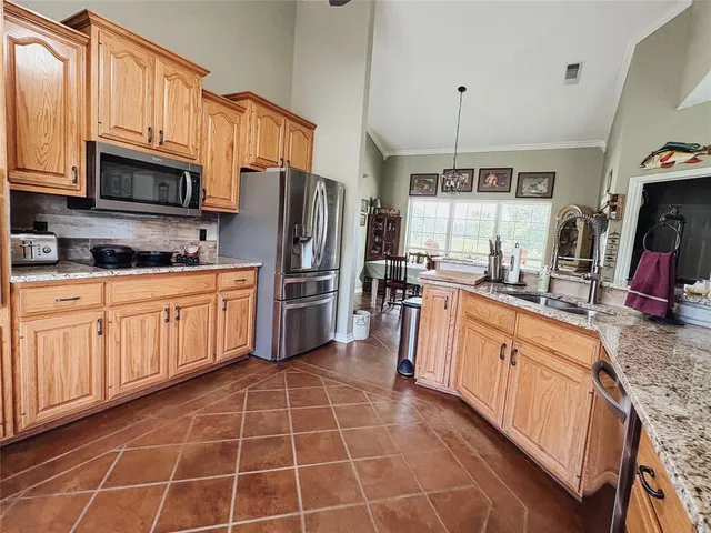 a kitchen with stainless steel appliances granite countertop a sink stove refrigerator and cabinets