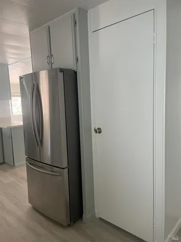 a view of a refrigerator in kitchen and an empty room