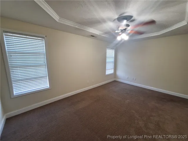 en empty room with windows and chandelier fan