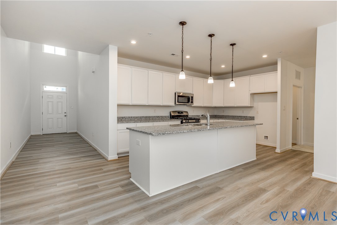 a view of kitchen with granite countertop refrigerator stove top oven and cabinets