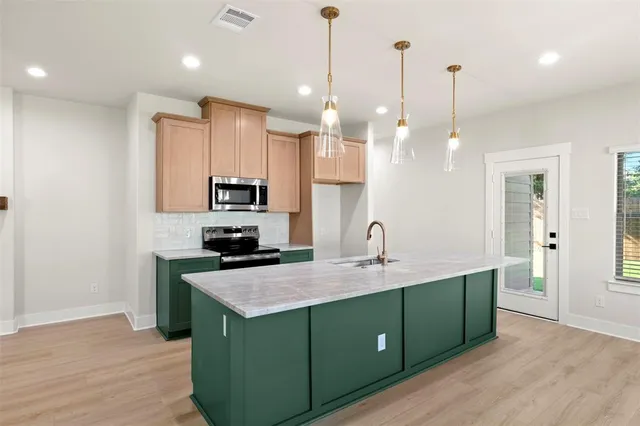 a kitchen with kitchen island a refrigerator a sink and cabinets