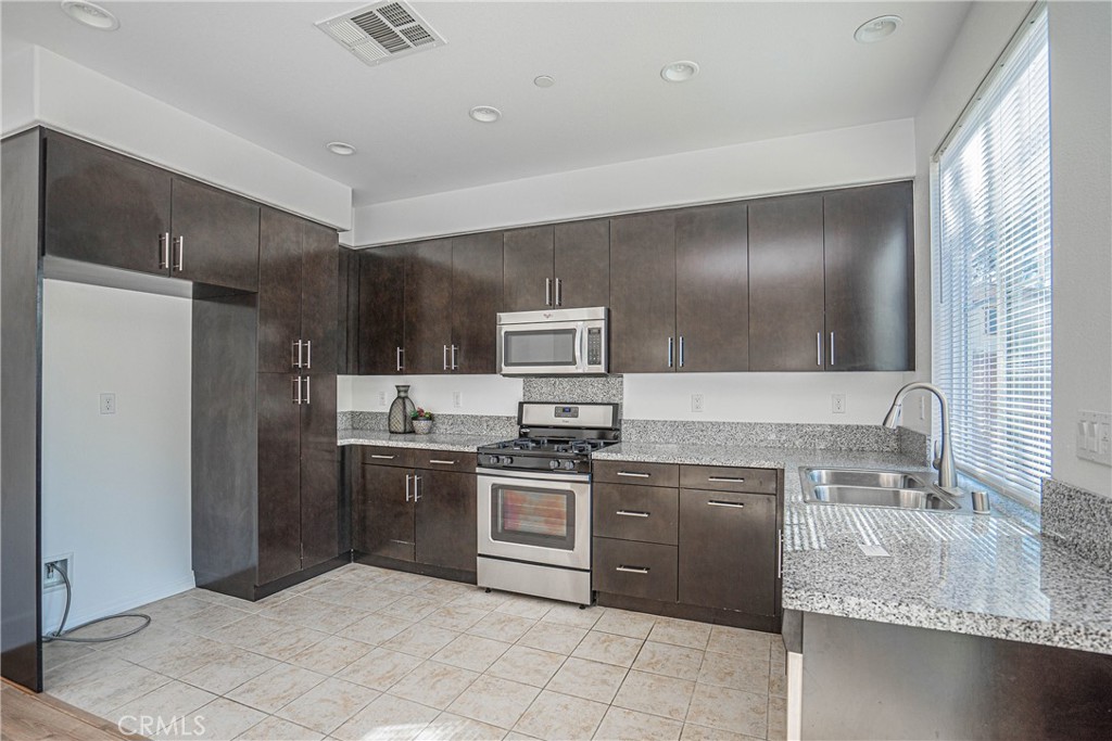 645 Liberation Way Fullerton, CA 92832 - Photo 4 of 20 a kitchen with stainless steel appliances granite countertop a sink stove and refrigerator