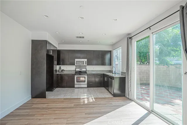 a kitchen with stainless steel appliances granite countertop a refrigerator a sink a stove top oven and a counter space