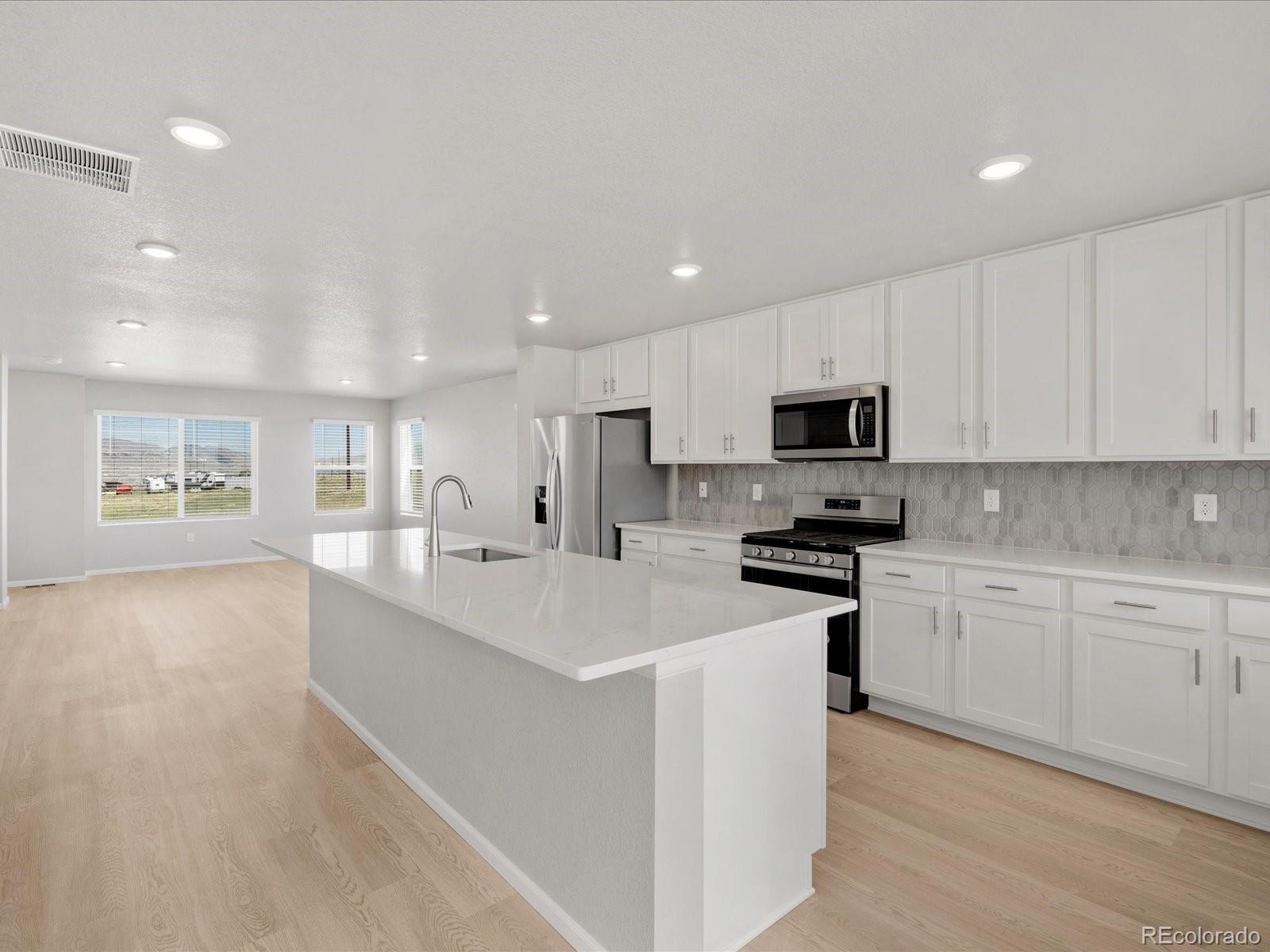 14451 Pansy Loop Morrison, CO 80465 - Photo 4 of 34 a large white kitchen with stainless steel appliances granite countertop lots of white cabinets a stove and a sink