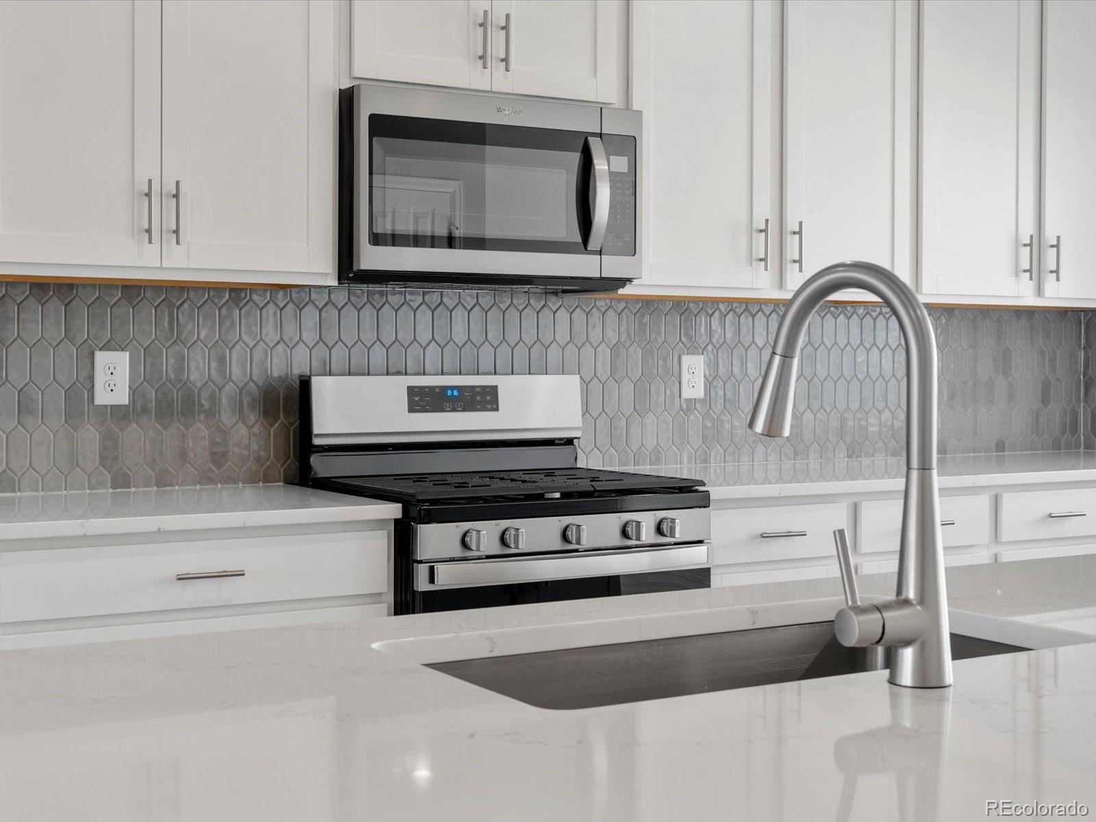 14451 Pansy Loop Morrison, CO 80465 - Photo 8 of 34 a kitchen with granite countertop white cabinets and stainless steel appliances