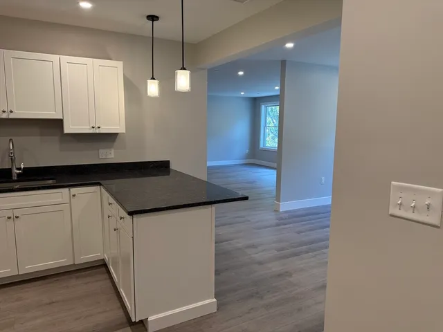 a kitchen with stainless steel appliances granite countertop a sink a stove a refrigerator and white cabinets with wooden floor