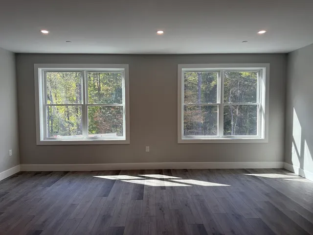 a view of an empty room with wooden floor and closet