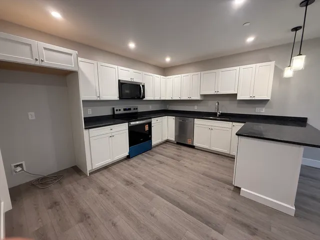 a kitchen with granite countertop white cabinets and black appliances