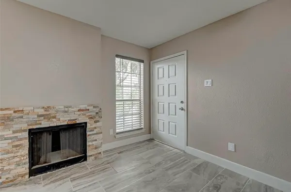 an empty room with wooden floor fireplace and windows