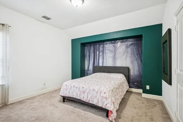 a bedroom with a bed and a flat tv screen on dresser