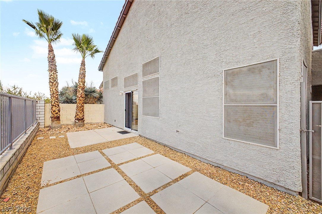 2316 Ramsgate Drive Henderson, NV 89074 - Photo 27 of 28 A private outdoor space features a patterned concrete patio with lush palms against a clean stucco exterior.