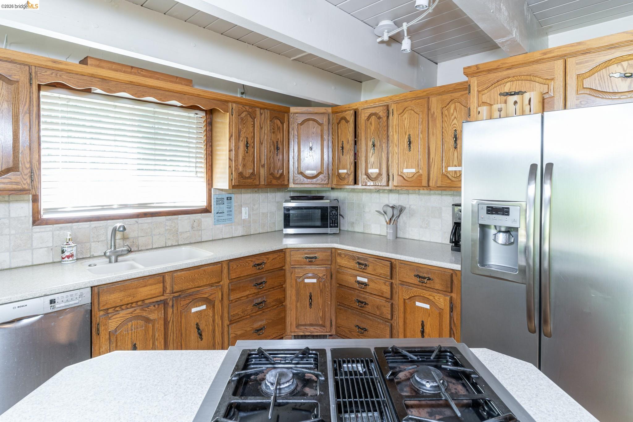 19390 Ferretti Road Groveland, CA 95321 - Photo 17 of 38 Kitchen featuring wood cabinetry, white countertops, tile backsplash, and stainless steel appliances
