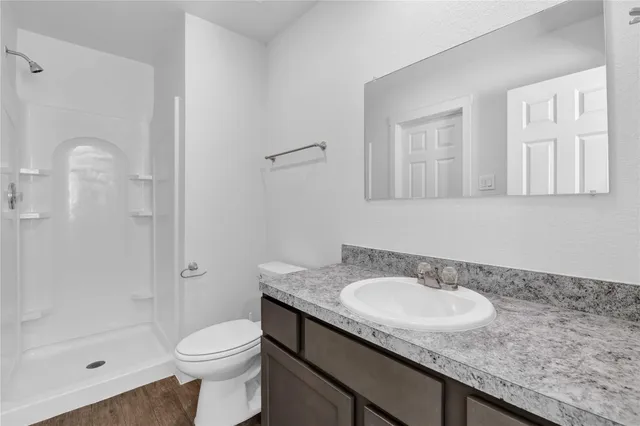a bathroom with a granite countertop sink a toilet and shower