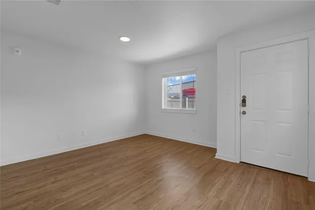 a view of an empty room with wooden floor and a window