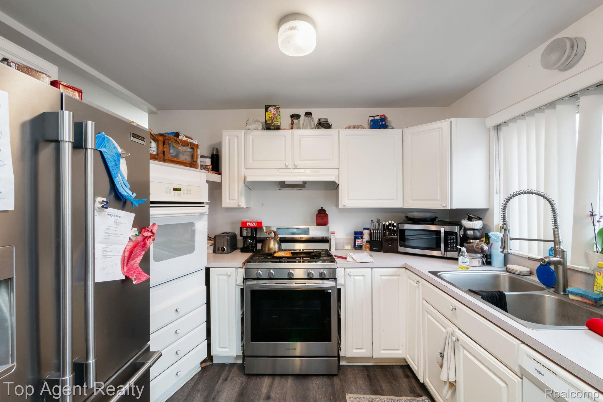 2065 Ridgemont Street Commerce Township, MI 48382 - Photo 13 of 35 Kitchen with stainless steel appliances, light countertops, white cabinetry, and dark wood-style floors