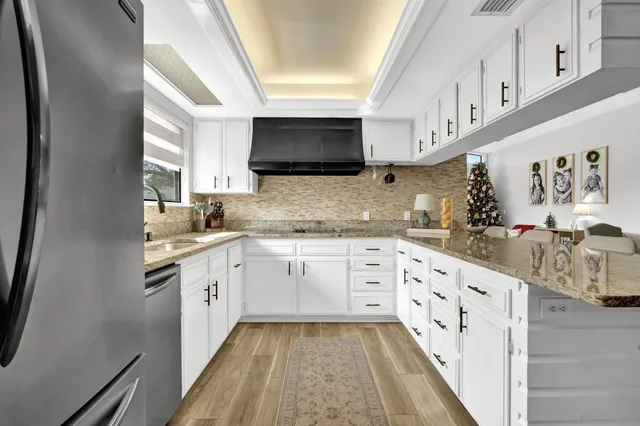 a kitchen with granite countertop a sink and white cabinets