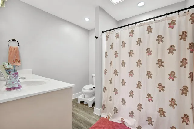 a bedroom with a bed and dresser with wooden floor