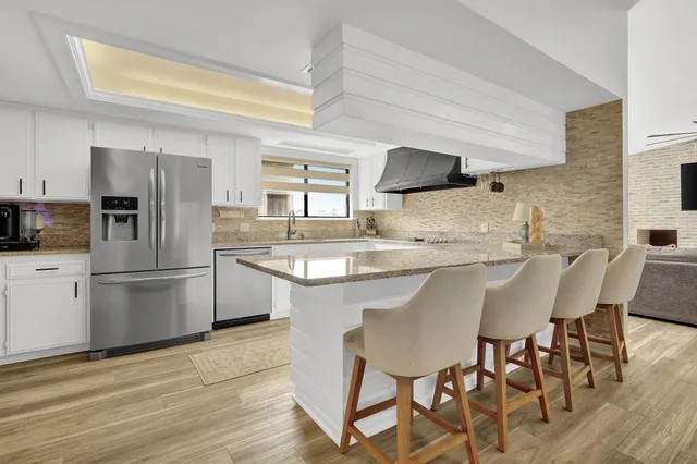 a kitchen with stainless steel appliances granite countertop a refrigerator and a sink