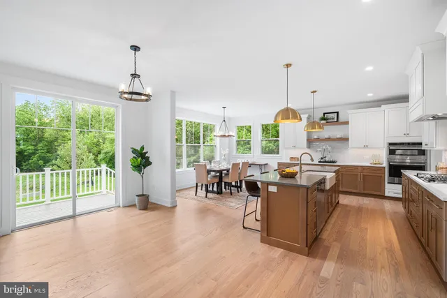 a large kitchen with stainless steel appliances granite countertop a sink a stove and a wooden floors