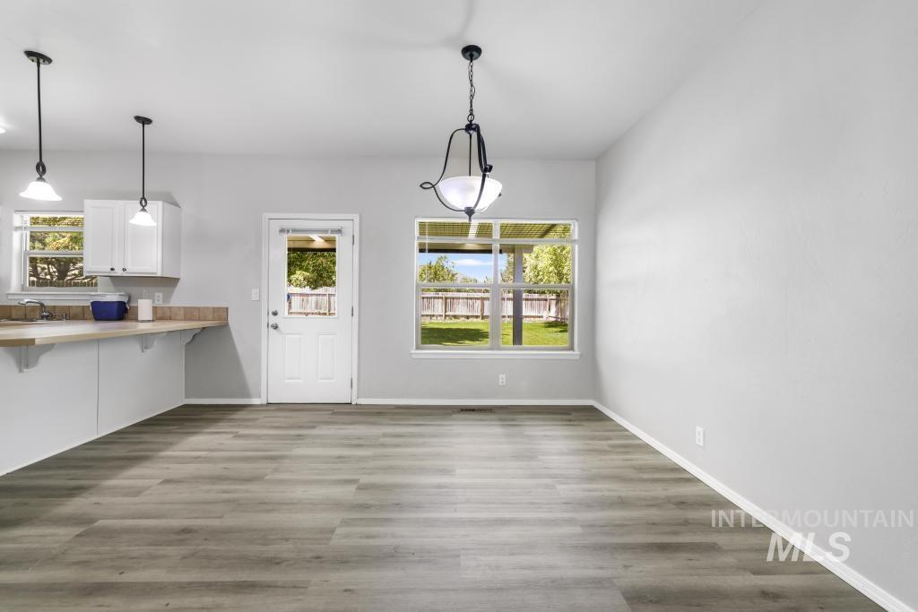 1183 Cortes Loop Twin Falls, ID 83301 - Photo 8 of 30 Open-concept dining area featuring wood-finish flooring, a contemporary chandelier, and a bright window overlooking the backyard