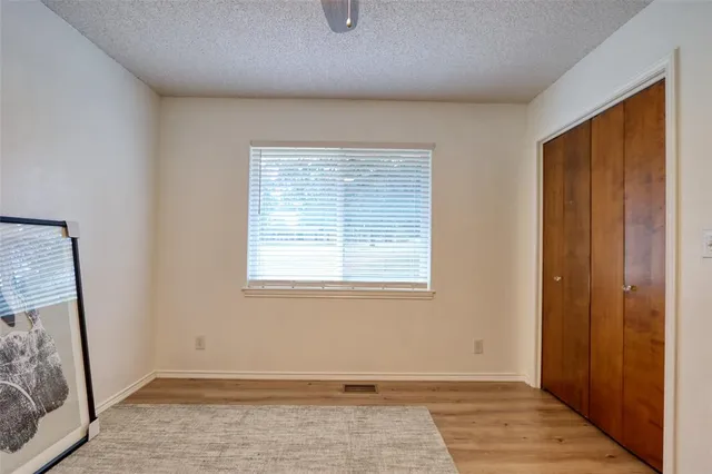 a view of an empty room with window and wooden floor