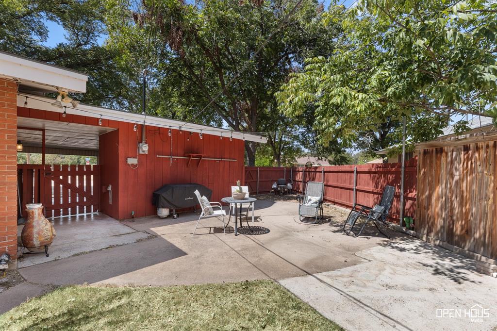 4419 Randel Drive Wichita Falls, TX 76308 - Photo 27 of 32 Paved patio area with a covered section, wood fencing, and mature trees