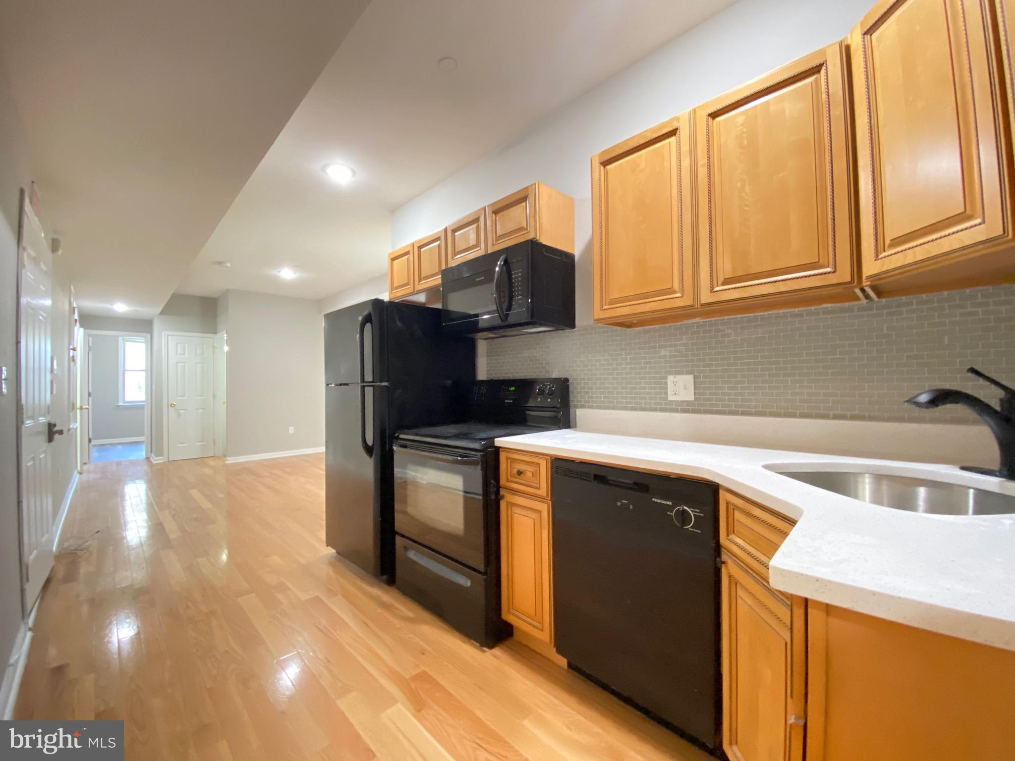 a kitchen with stainless steel appliances granite countertop a sink and a stove top oven with wooden floor