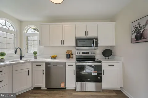 a kitchen with white cabinets stainless steel appliances and sink