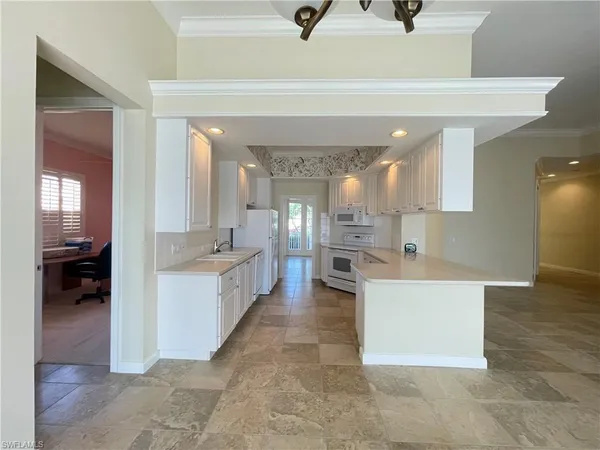a large white kitchen with a large counter top and stainless steel appliances