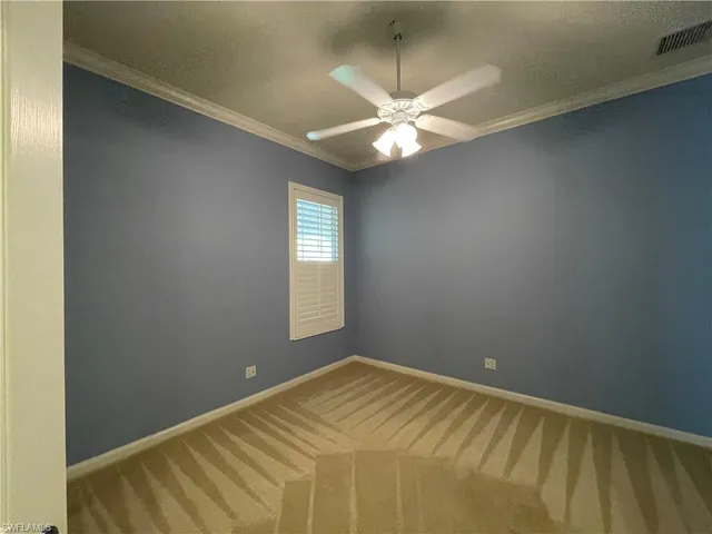 an empty room with a chandelier fan and windows