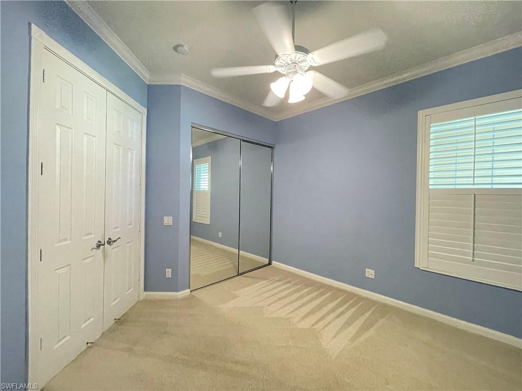 7025 Leopardi Court Naples, FL 34114 - Photo 24 of 48 an empty room with a chandelier fan and windows