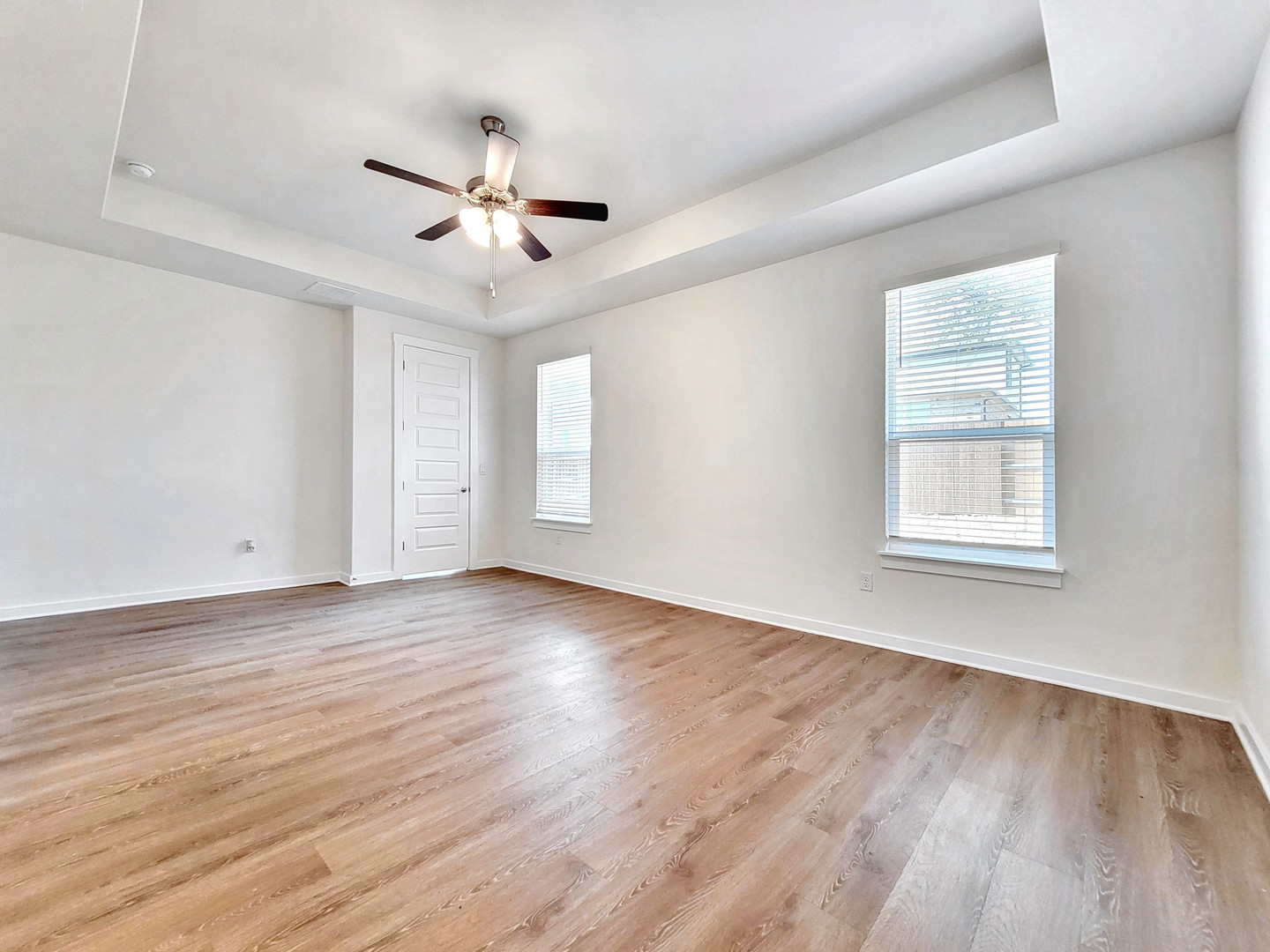 2329 Gabriels Horn Road Leander, TX 78641 - Photo 9 of 23 Natural light pours into this spacious primary bedroom, featuring a tray ceiling and wood-look flooring.