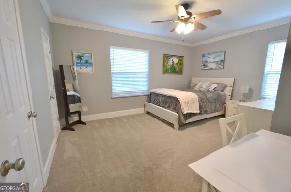 a bed sitting in a spacious bedroom next to a window and a larger closet