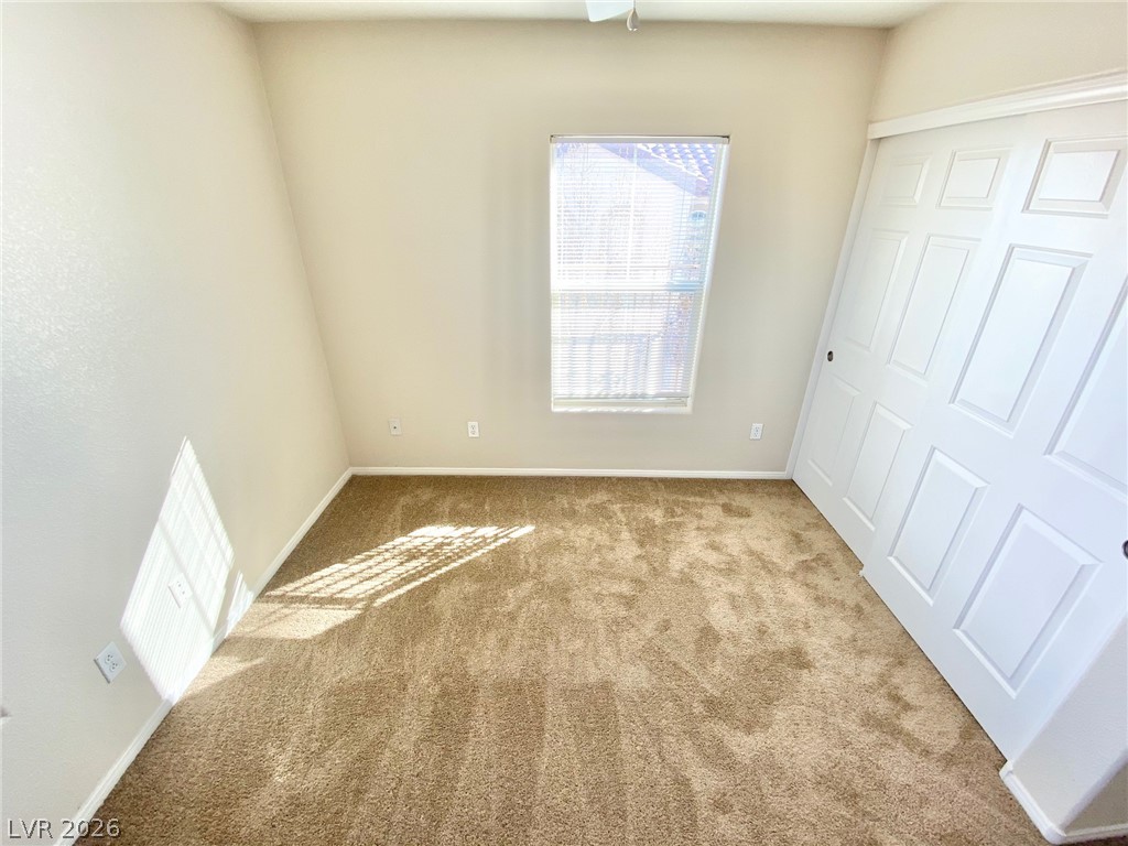 8569 Rhamus Court Las Vegas, NV 89149 - Photo 12 of 35 A well-lit bedroom features plush carpeting and convenient sliding closet doors.