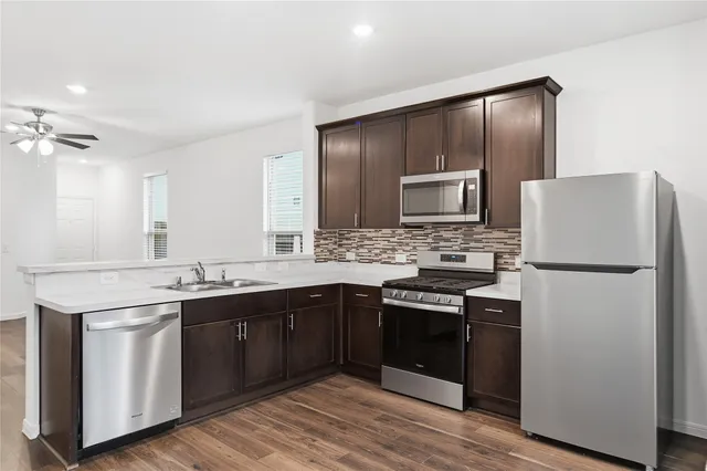 a kitchen with granite countertop stainless steel appliances and wooden floor