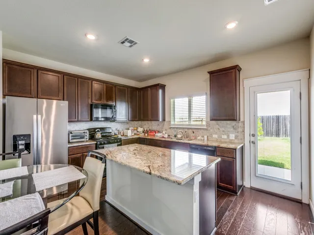 a kitchen with a sink a counter top space stainless steel appliances cabinets and a window