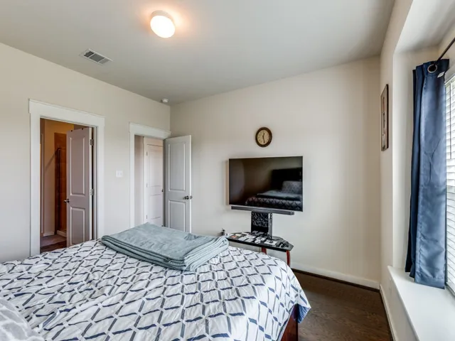 a bedroom with a bed and a flat tv screen on wall