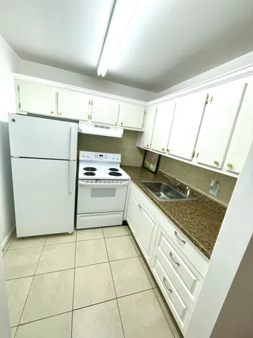 a kitchen with a refrigerator a stove a sink and a window