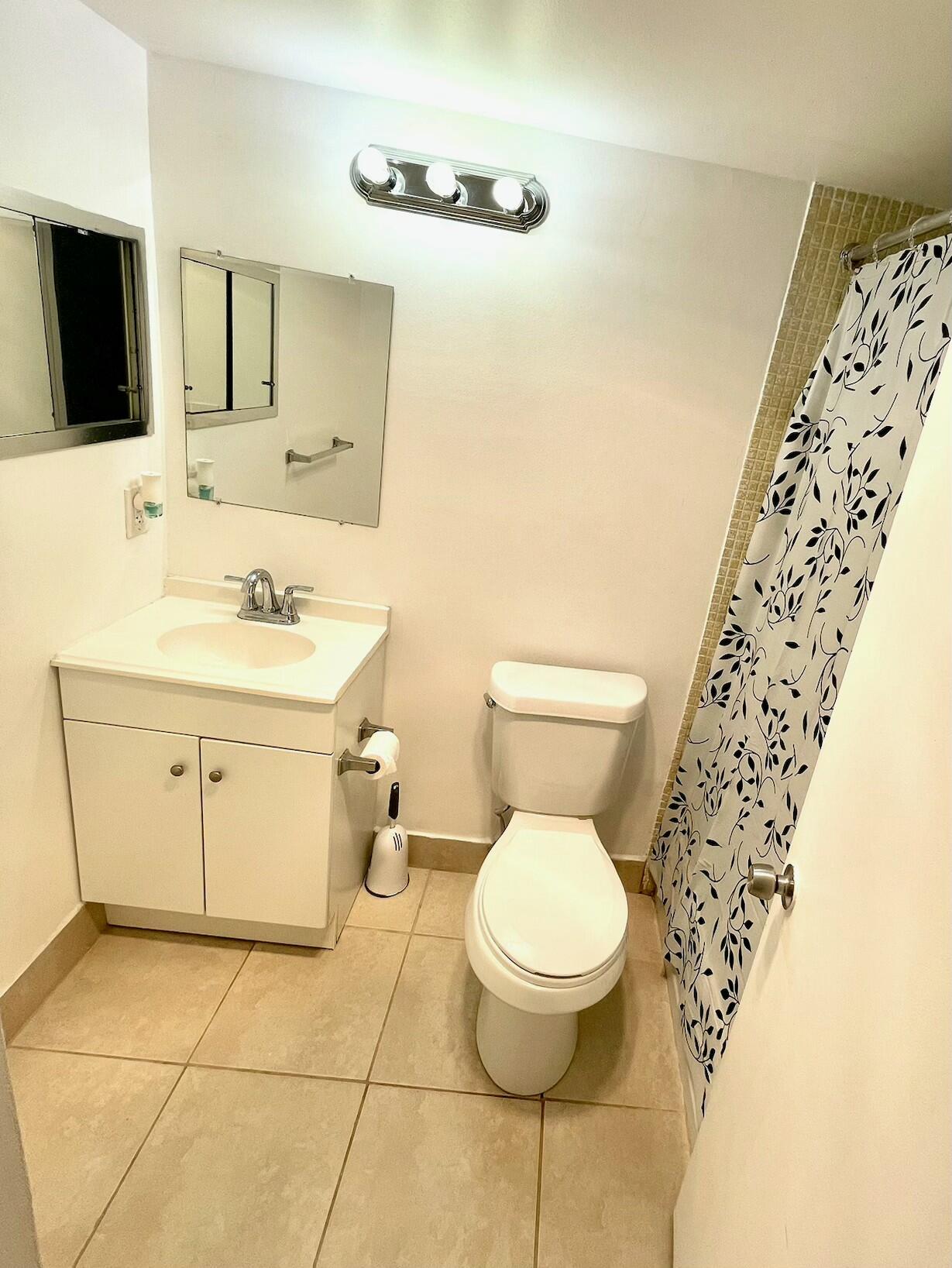 128 Canterbury F, Unit 128 West Palm Beach, FL 33417 - Photo 5 of 17 a bathroom with a toilet sink and mirror