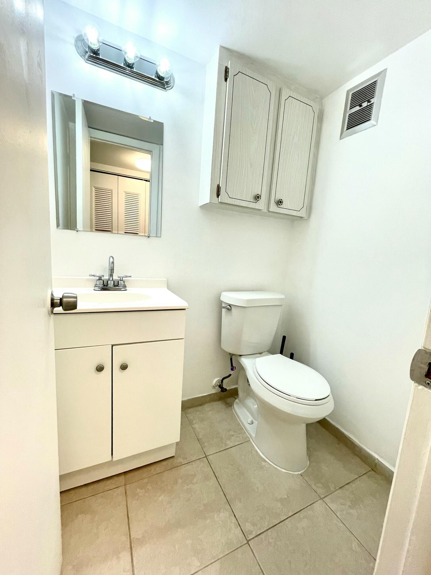 128 Canterbury F, Unit 128 West Palm Beach, FL 33417 - Photo 6 of 17 a bathroom with a toilet sink and mirror