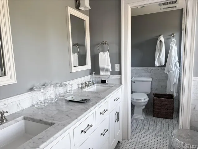 a bathroom with a granite countertop sink mirror and toilet