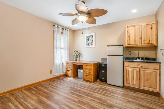 a kitchen with stainless steel appliances granite countertop a refrigerator a stove a sink and white cabinets with wooden floor