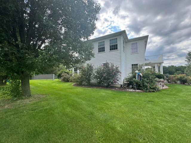 a view of a backyard with plants and large tree