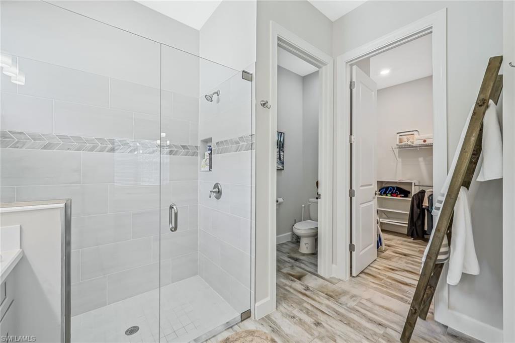 15495 Rio Ponace Court Naples, FL 34114 - Photo 14 of 43 Full bathroom with a stall shower, wood finished floors, a walk in closet, and vanity